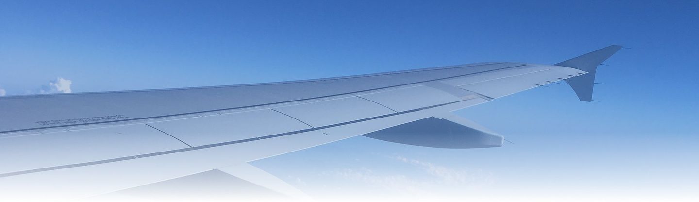 Aile d'avion au-dessus des nuages ​​sur fond de ciel bleu, vue par une fenêtre