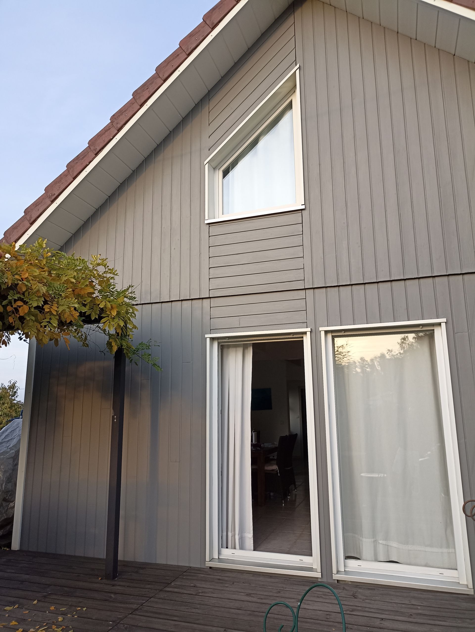 Main gantée peignant au rouleau une clôture en bois à l'extérieur, sous une lumière chaude