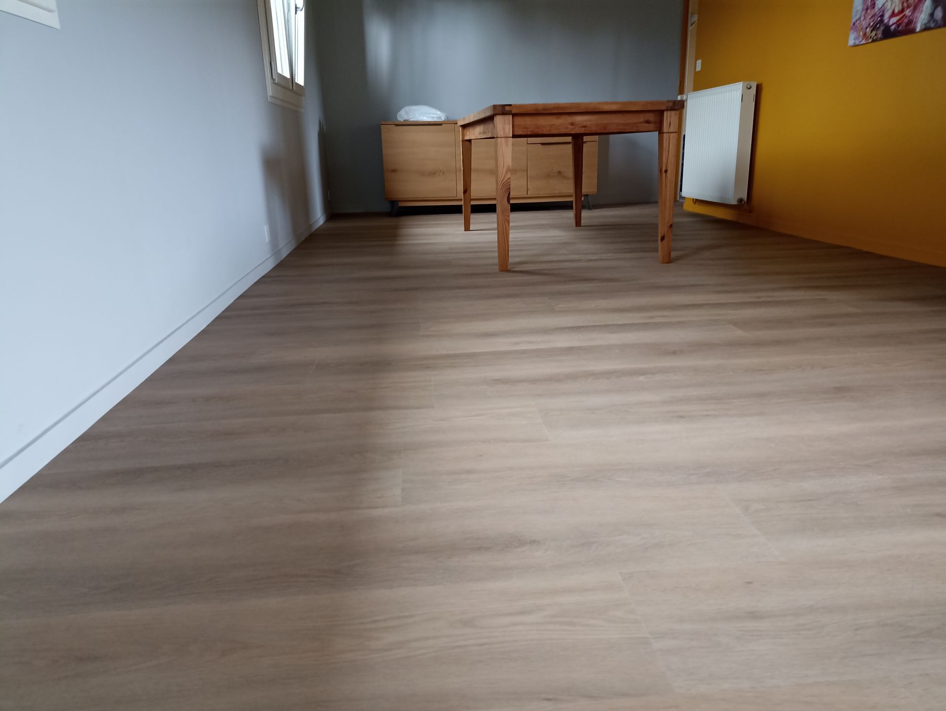 Pièce vide avec parquet clair, table en bois, chaise et mur d'accent jaune