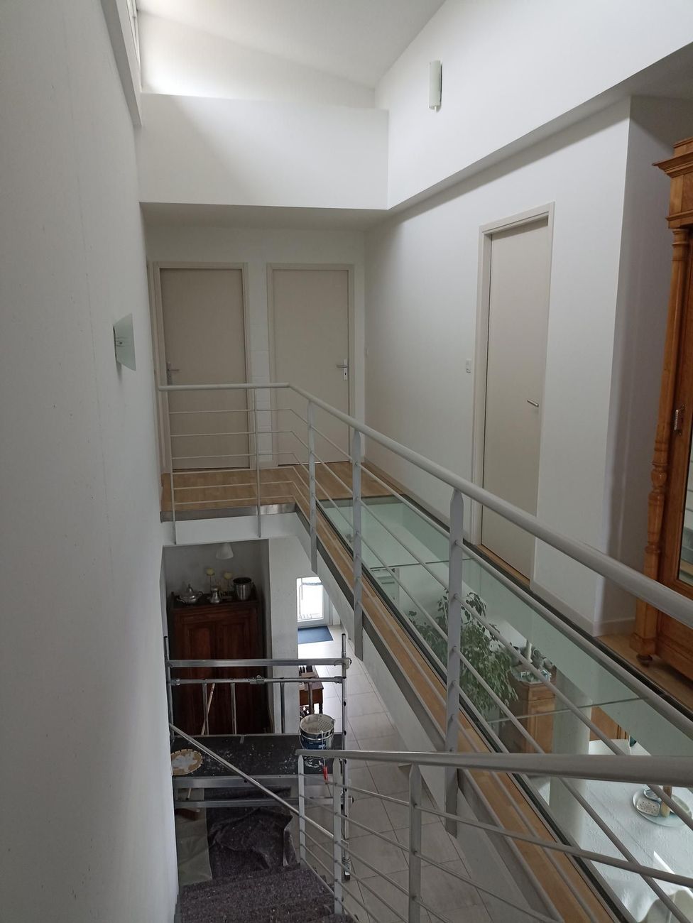 Couloir intérieur avec balustrade en verre et portes donnant sur un étage inférieur