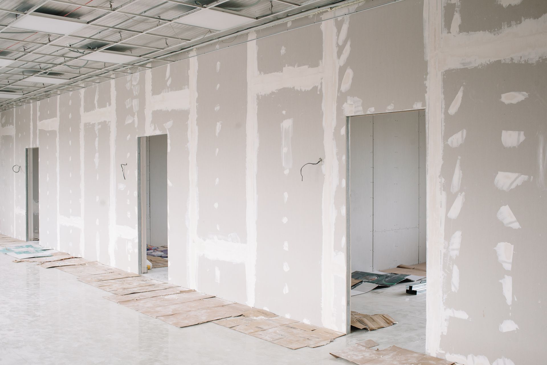 Intérieur partiellement fini avec cloisons sèches, portes ouvertes et débris de construction au sol