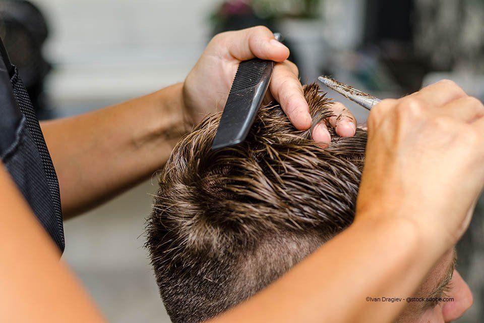 Friseurin bei Salon Bellissima schneidet die Haare eines Mannes