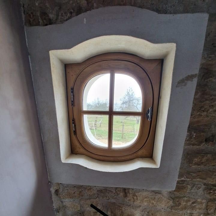 Une petite fenêtre en bois avec une vue sur un jardin