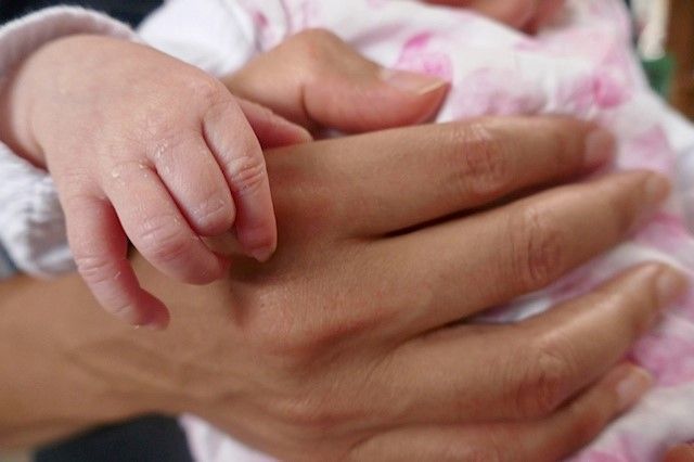 Une main de bébé avec une main d'adulte