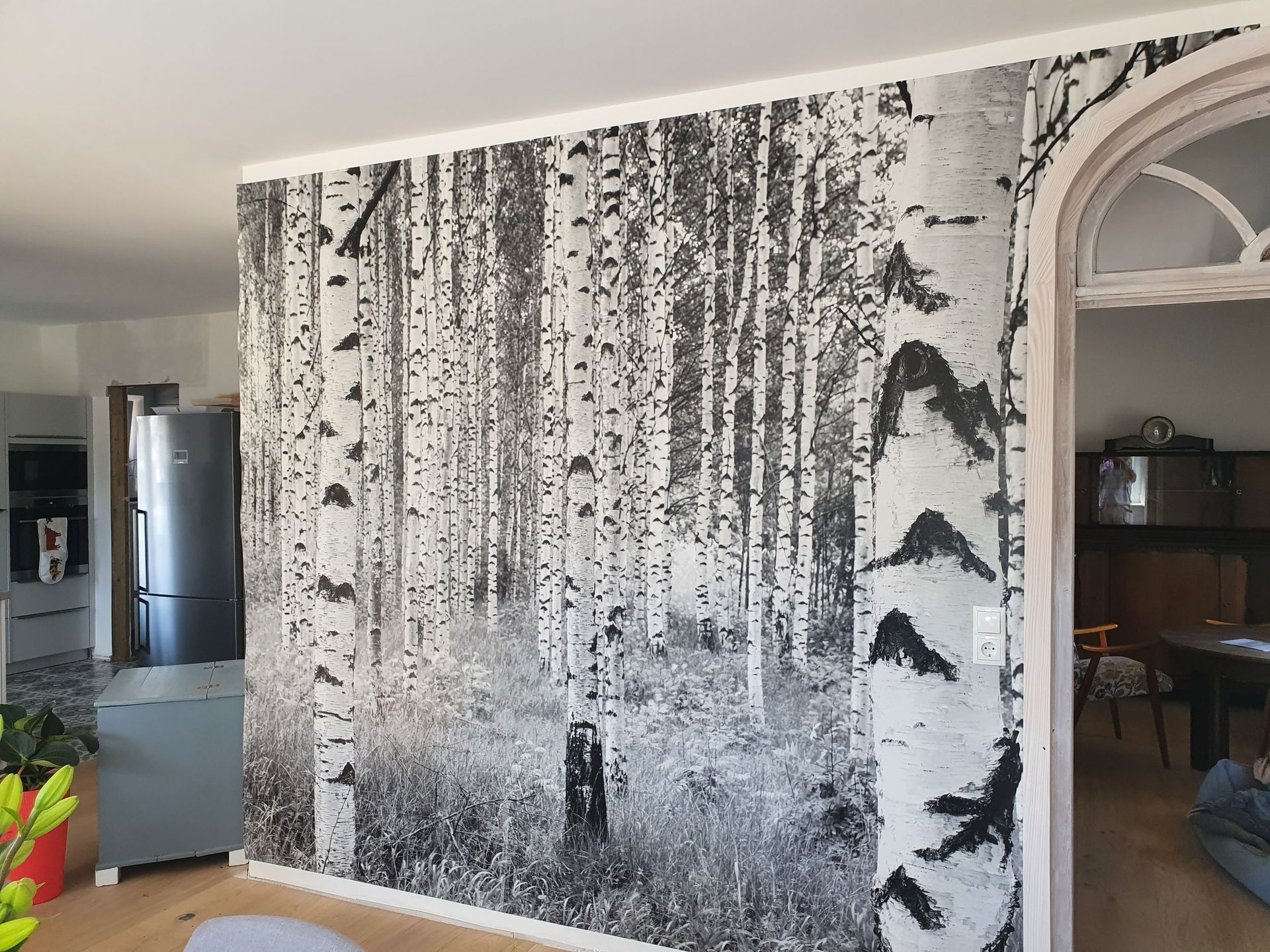 Wohnzimmer mit einer großen, schwarz-weißen abstrakten Wandmalerei und einem gewölbten Türbogen