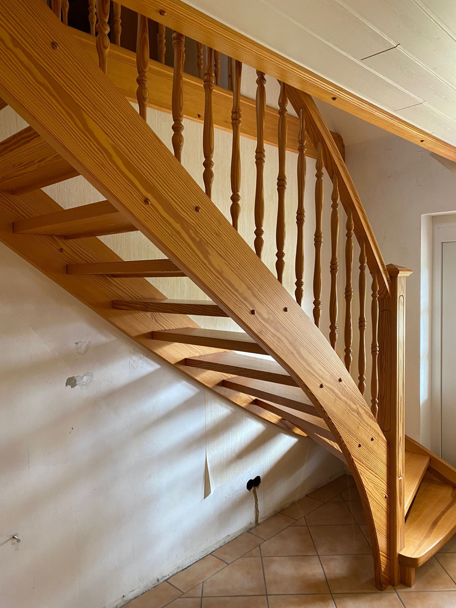 Holztreppe mit Geländer in einem kleinen gefliesten Innenraum