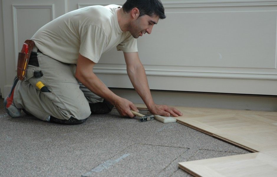 un homme pose un parquet