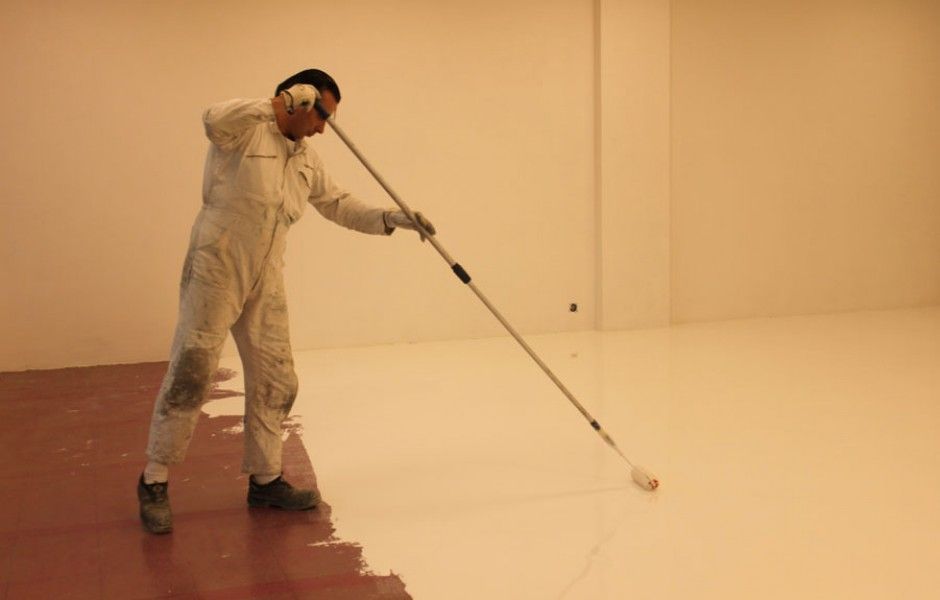 un homme peint un parquet en blanc