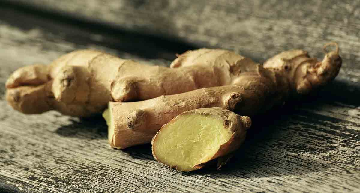 Racines de gingembre frais sur une surface rugueuse, dont un morceau coupé révèle un intérieur jaune