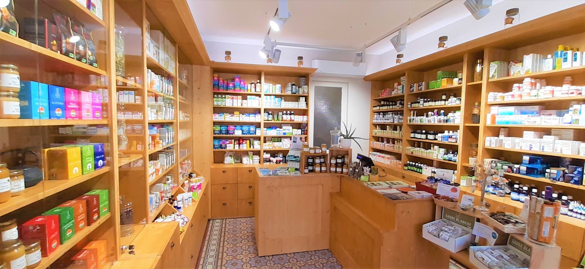 Allée de magasin bien éclairée, avec des étagères en bois remplies de bocaux et de boîtes colorés.