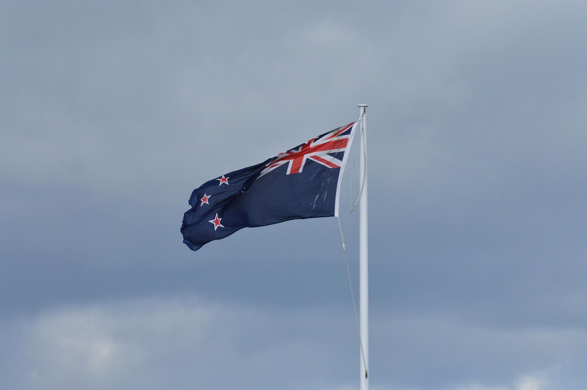 Drapeau néo-zélandais flottant au vent sur un mât sous un ciel nuageux