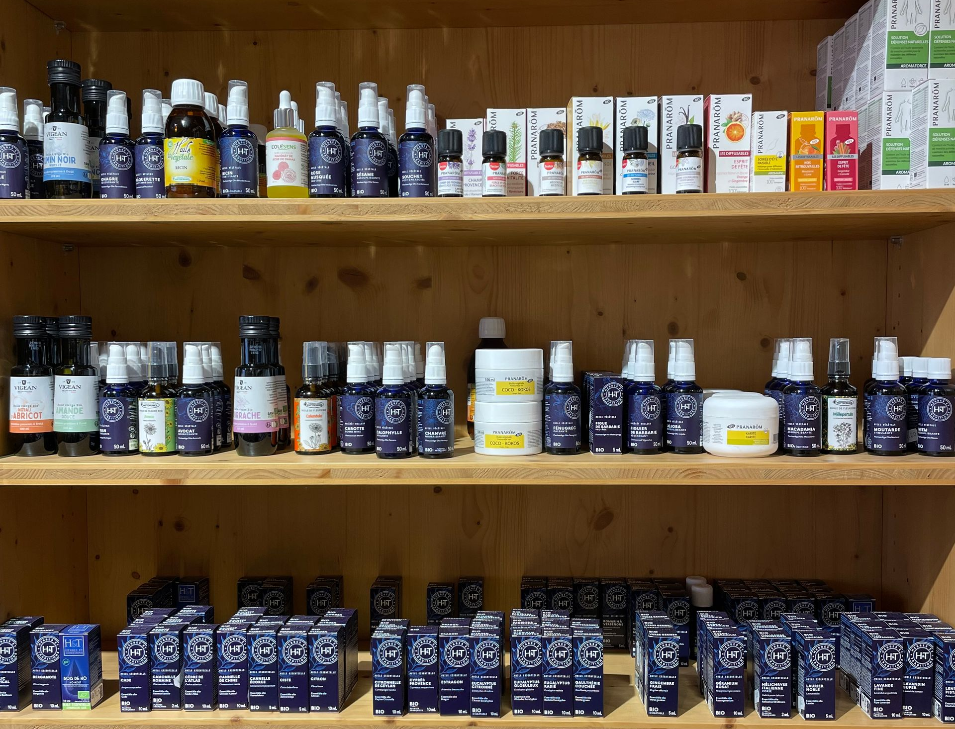 Des étagères en bois garnies de flacons et de boîtes de compléments alimentaires et de médicaments assortis.