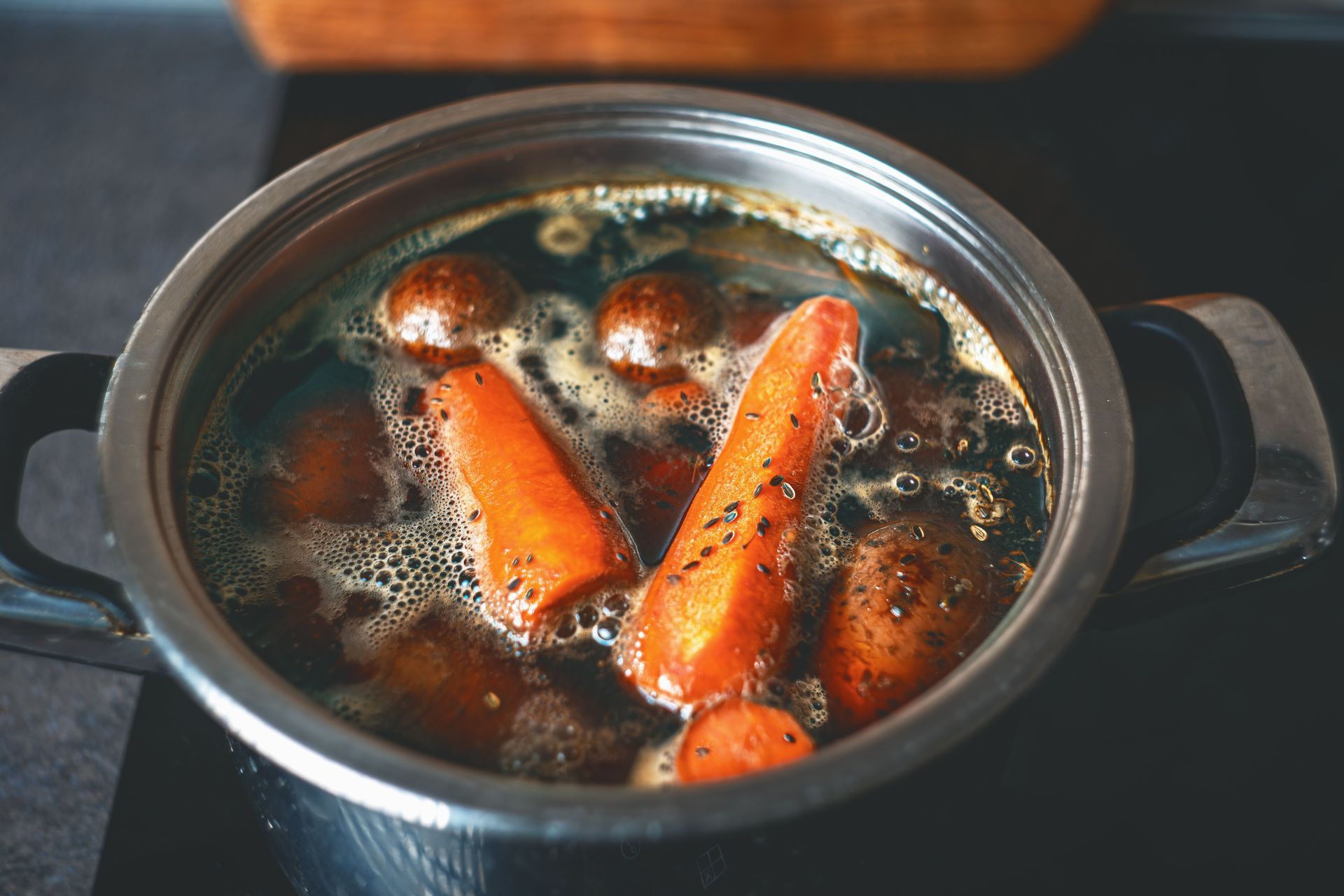 Une casserole de soupe mijotant avec des carottes et du bouillon foncé sur la cuisinière