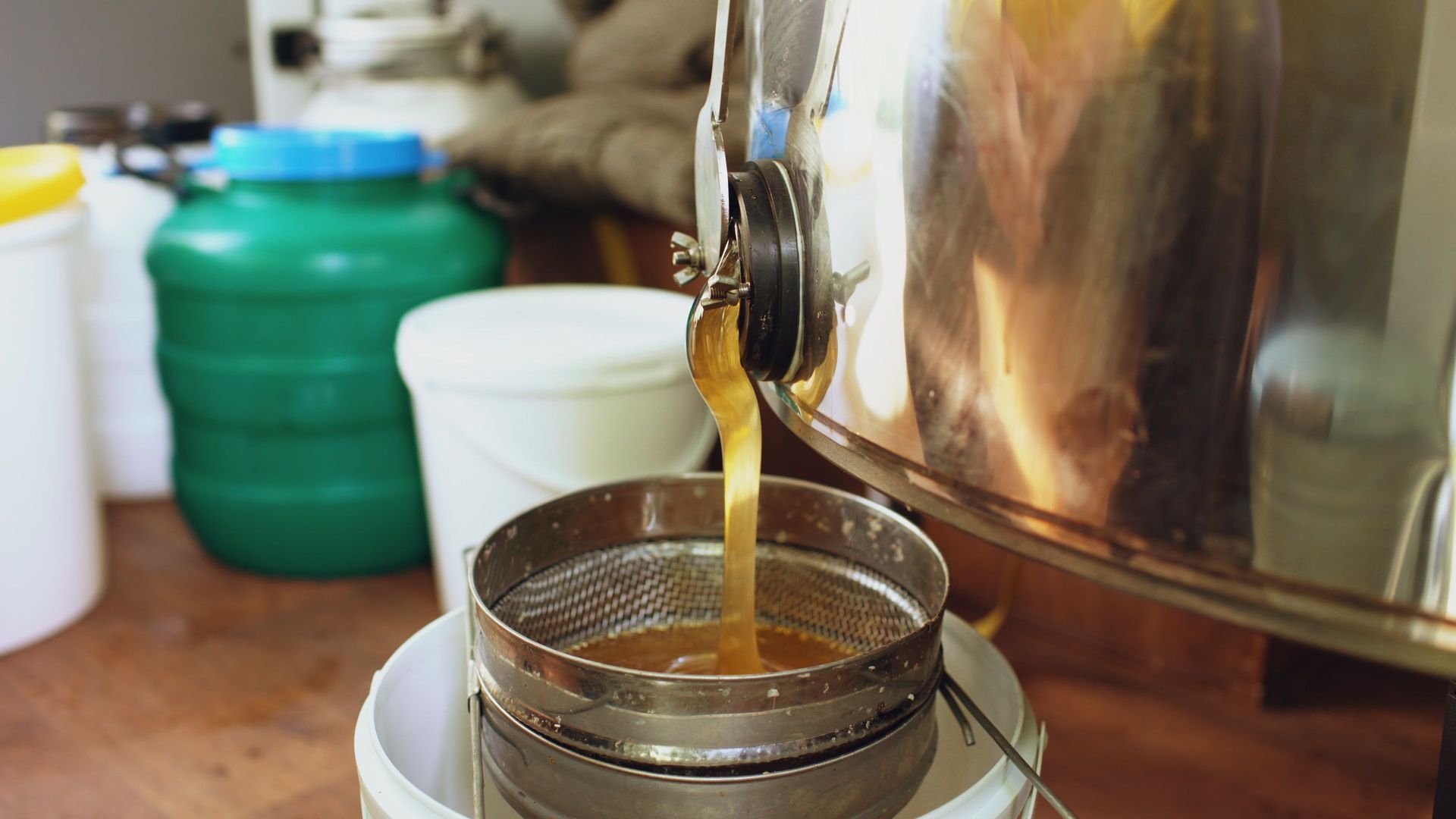 Du thé s'écoule à travers une passoire fine dans une tasse blanche posée sur le plan de travail de la cuisine.