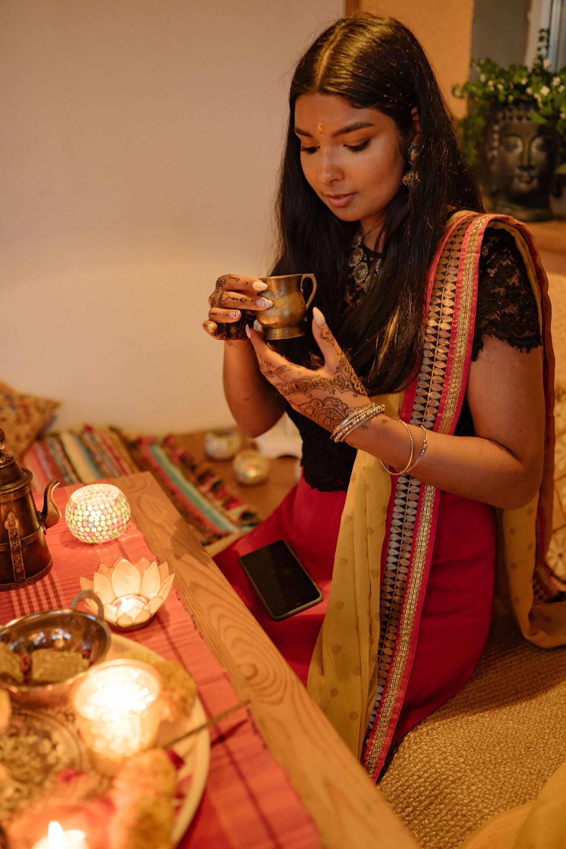 Femme en sari rouge à côté de bougies lors d'une fête en intérieur