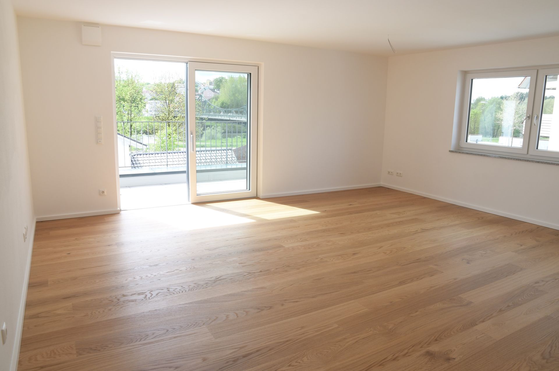 Ein leeres Wohnzimmer mit Hartholzböden und Glasschiebetüren.