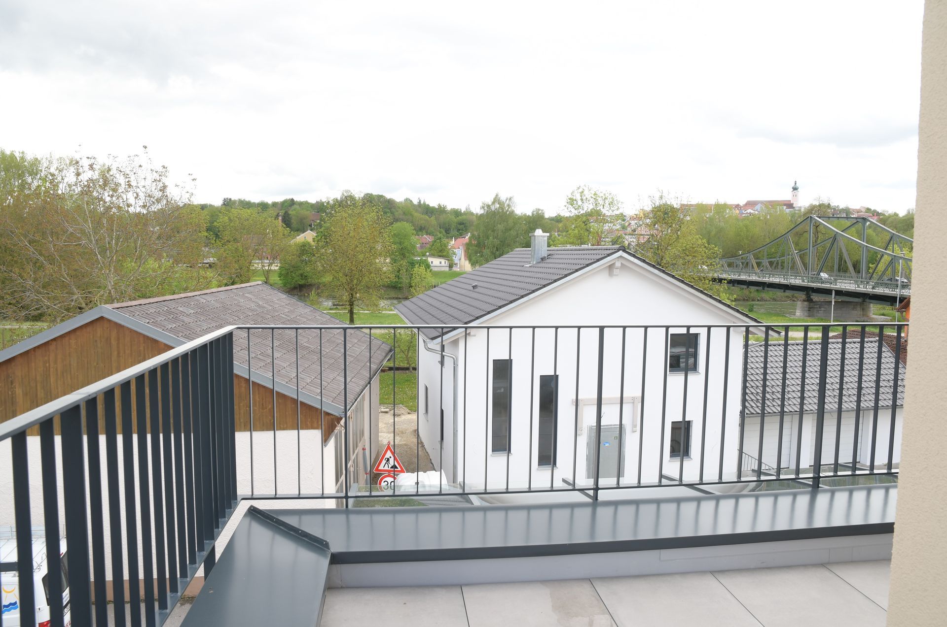 Ein Balkon mit Blick auf ein Haus und eine Brücke.