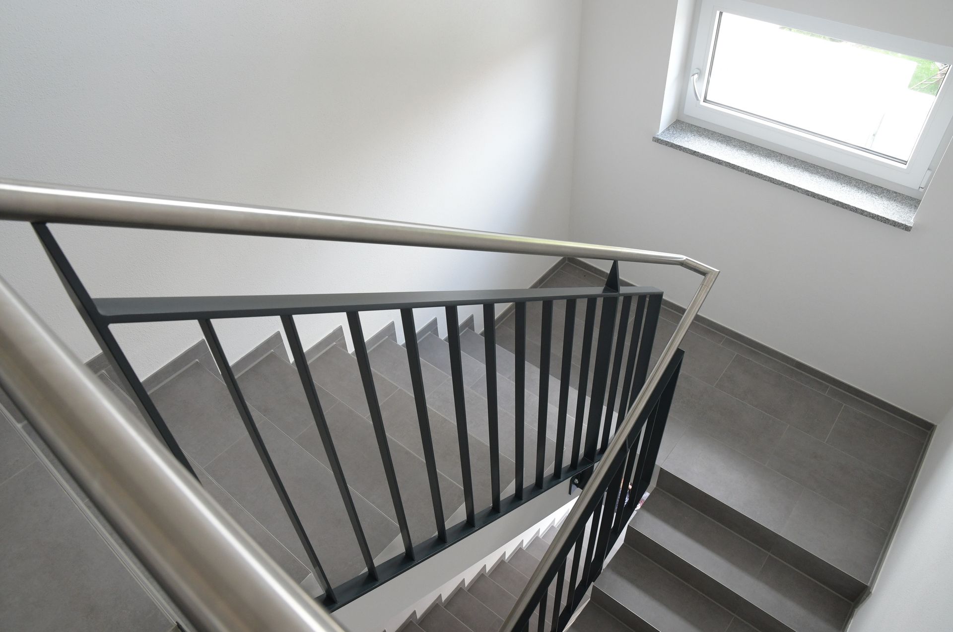 Eine Treppe mit einem Metallgeländer und einem Fenster