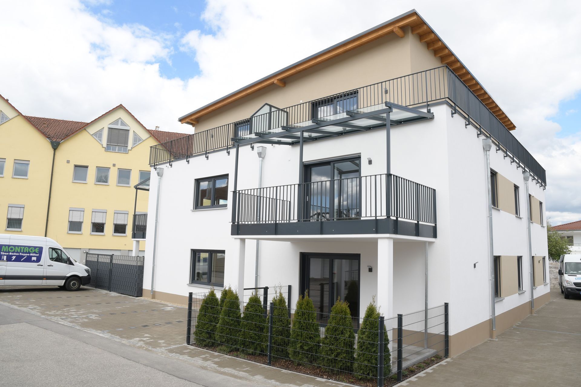 Ein weißer Lieferwagen parkt vor einem großen weißen Gebäude.