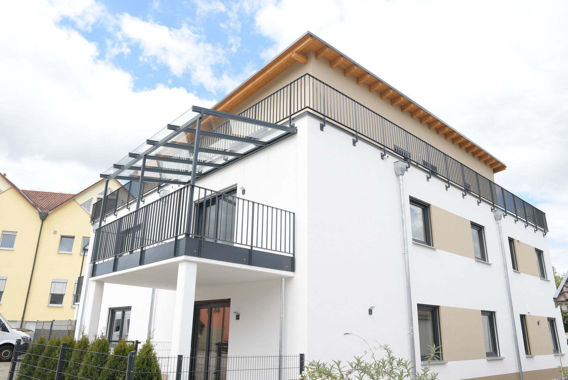 Ein weißes Haus mit einem Balkon und einem Baldachin darüber.