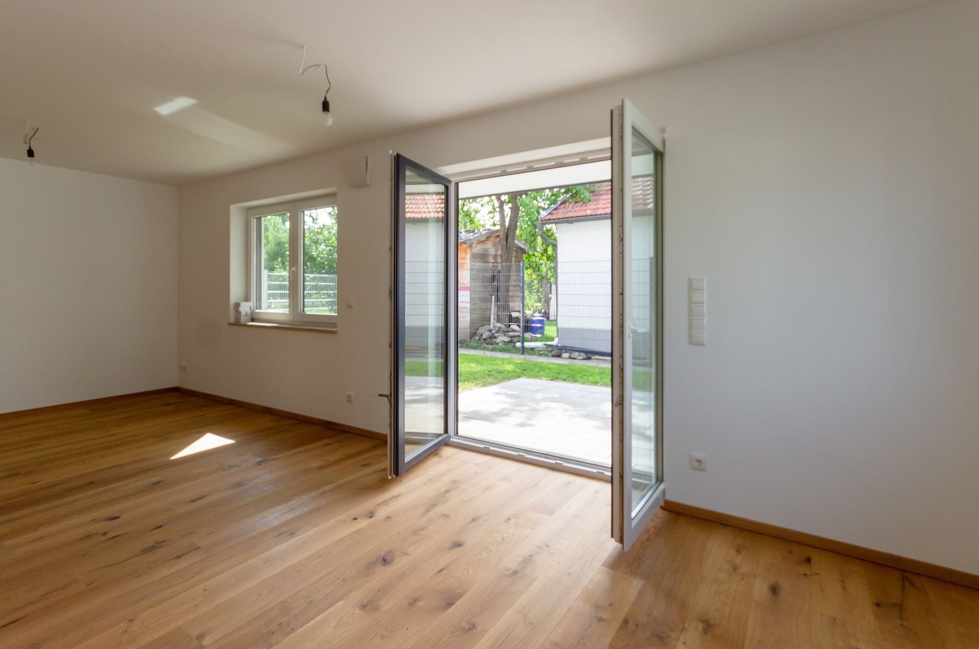 Ein leeres Wohnzimmer mit Hartholzböden und einem großen Fenster.