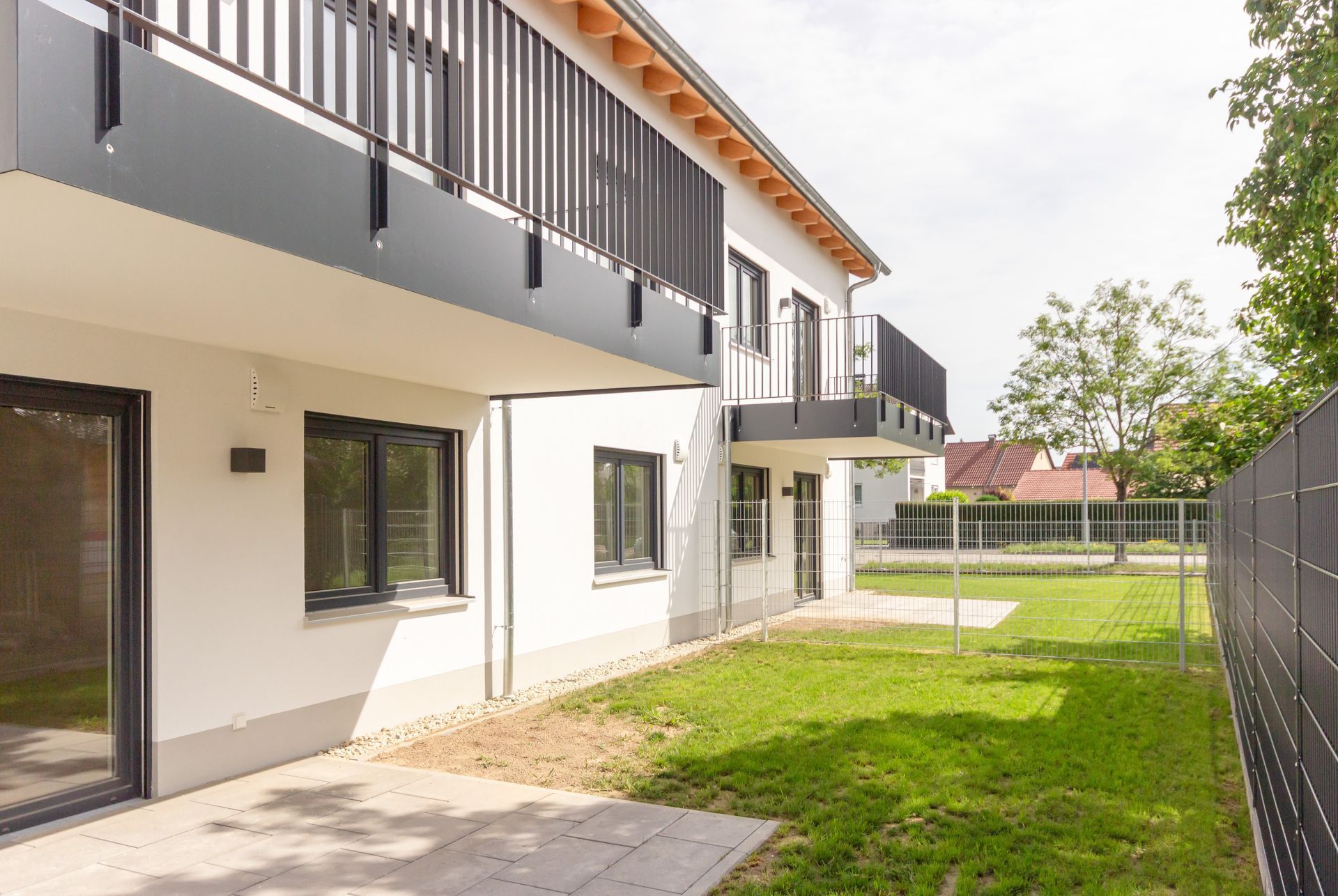 Ein weißes Haus mit einem Balkon und einem Zaun davor.