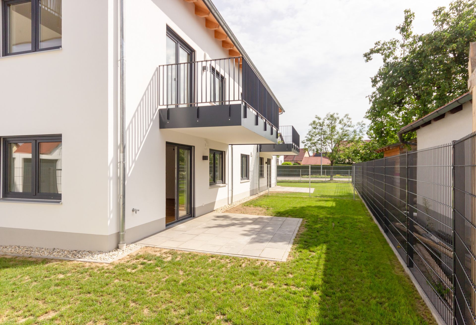 Ein weißes Haus mit einem Balkon und einem Zaun davor