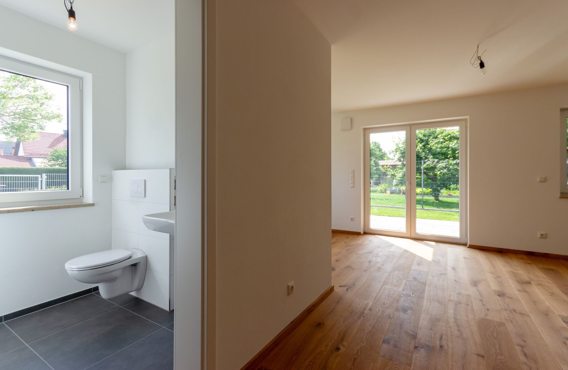 Ein leerer Raum mit Toilette, Waschbecken und Glasschiebetüren.