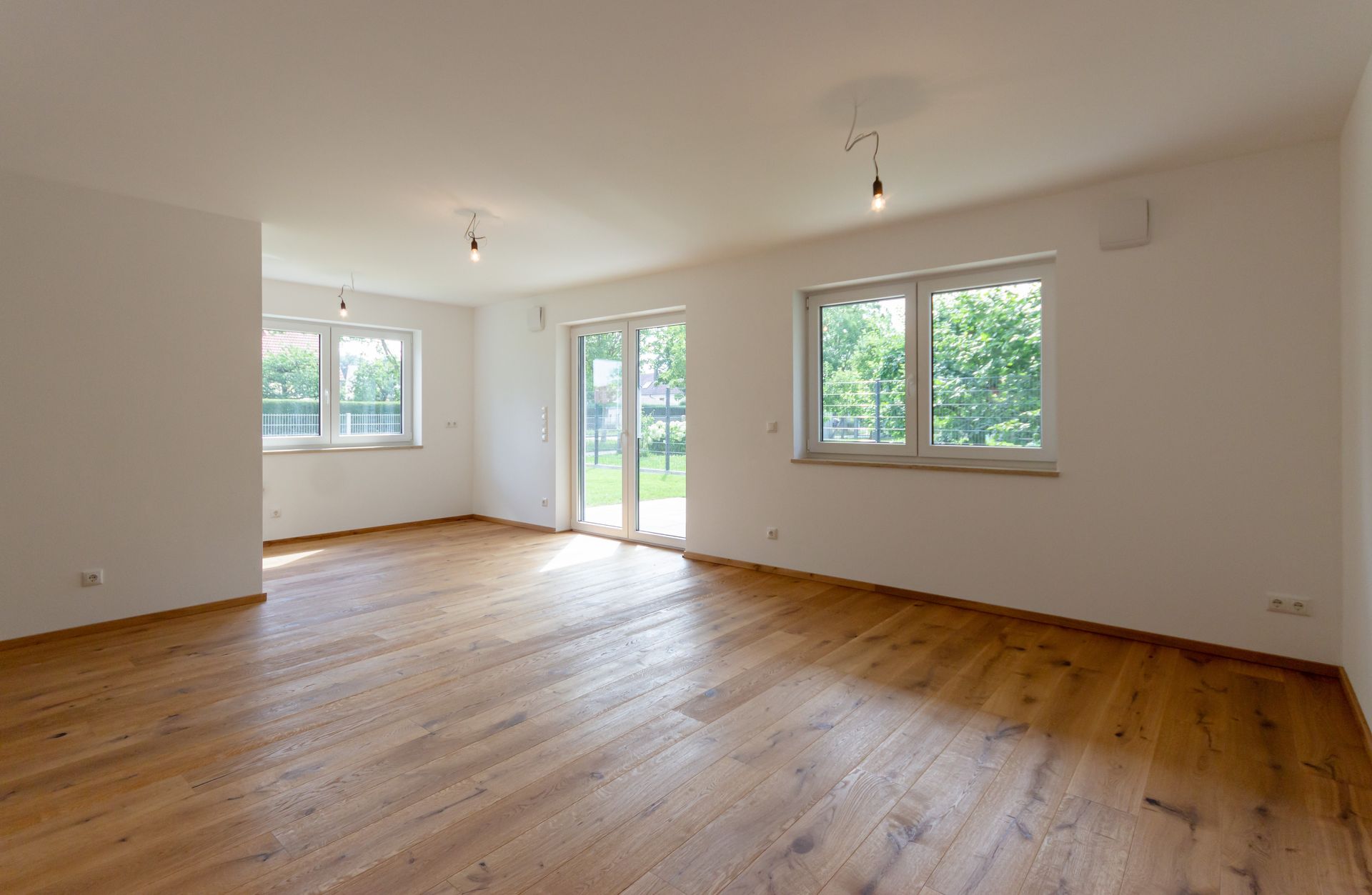 Ein leeres Wohnzimmer mit Hartholzböden und weißen Wänden.