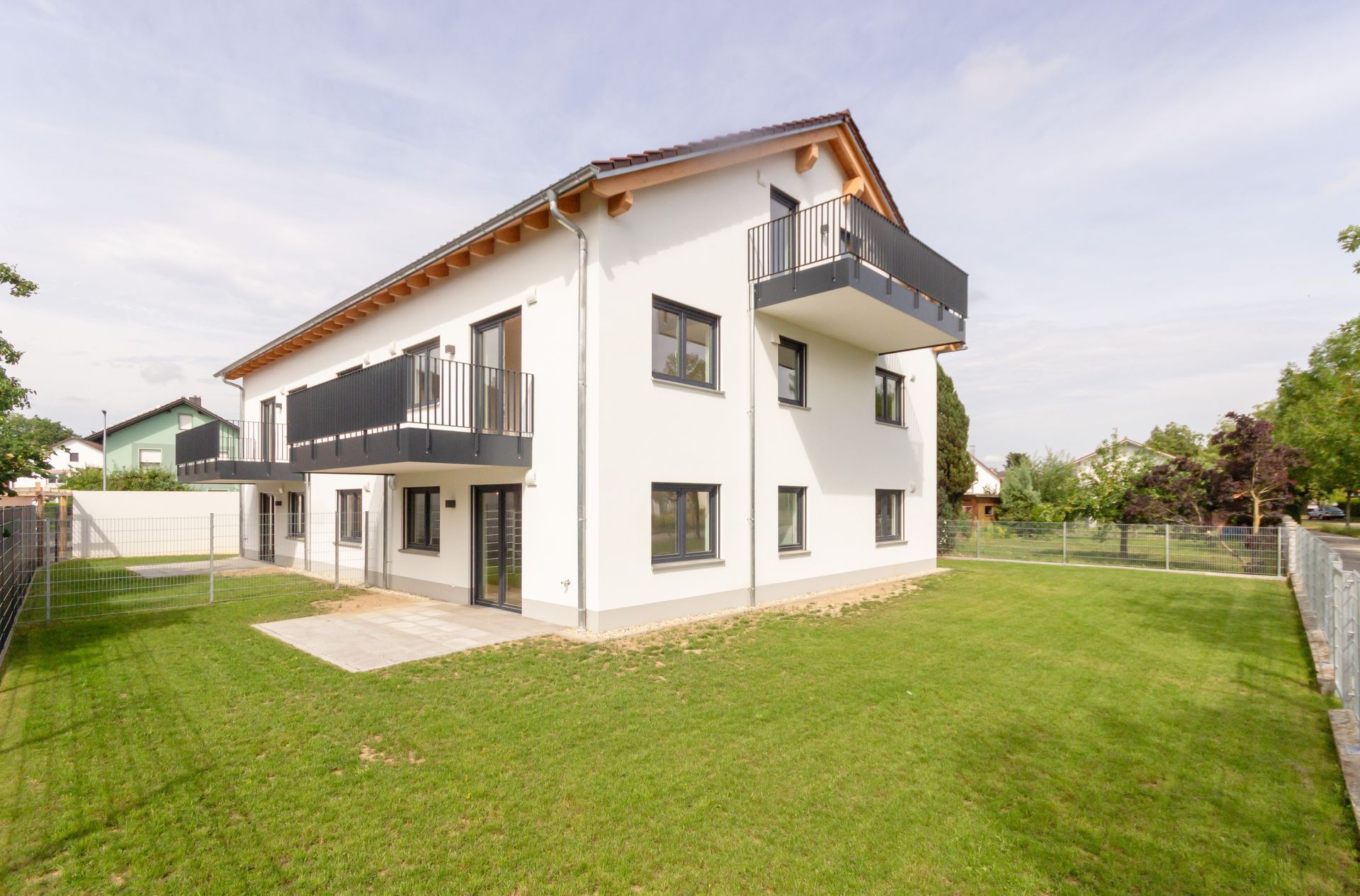 Ein großes weißes Haus mit Balkon und einer großen Wiese davor.