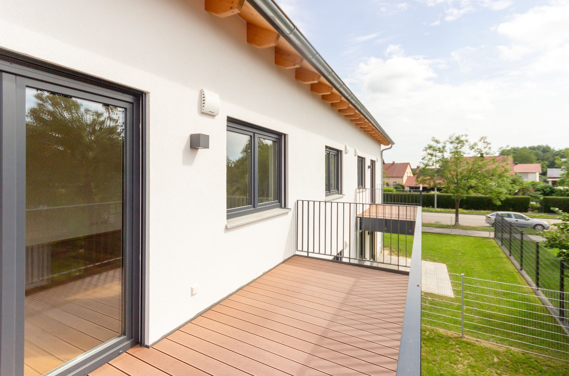 Ein Balkon an der Seite eines Hauses mit einer Holzterrasse
