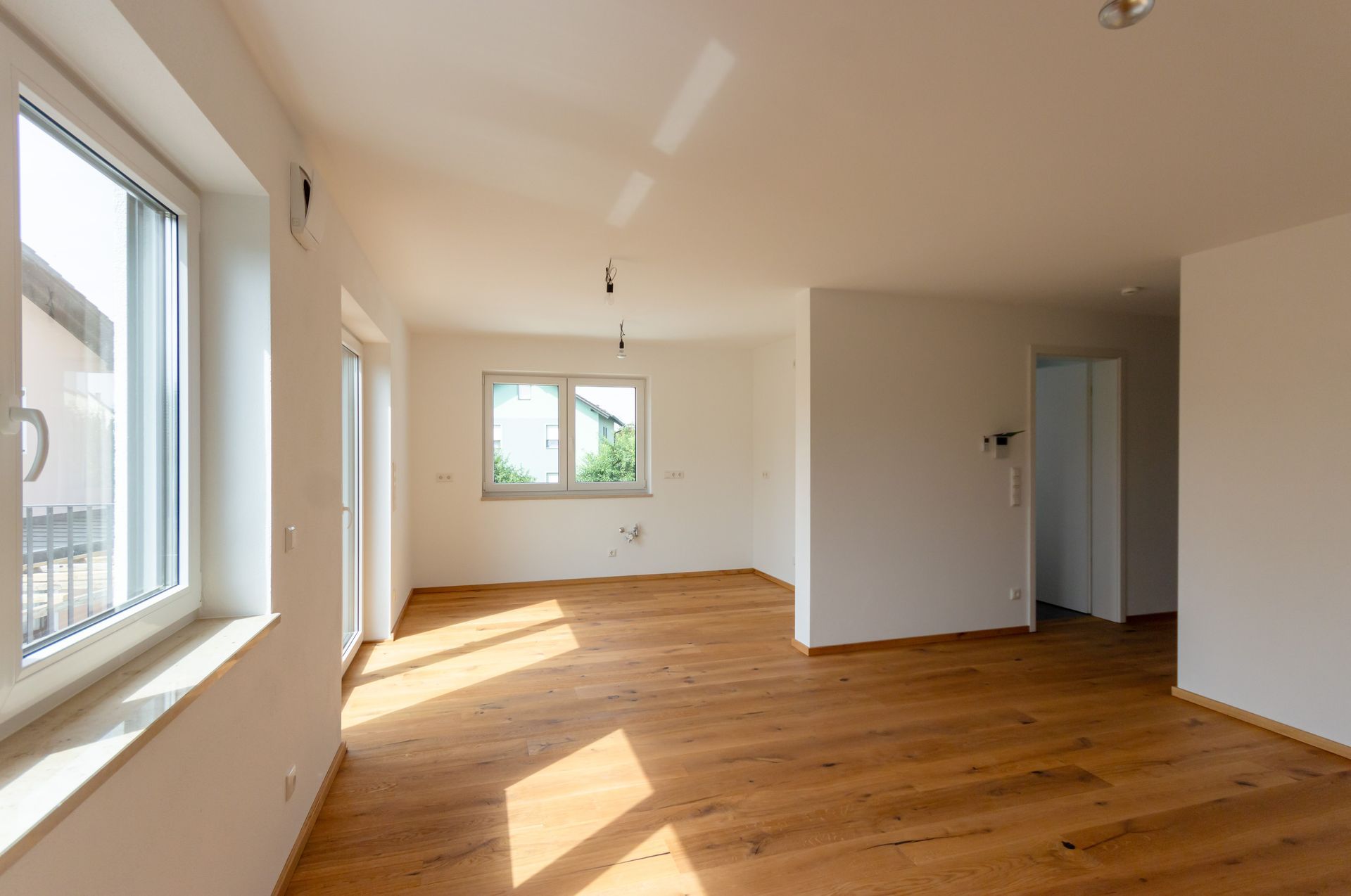 Ein leeres Wohnzimmer mit Hartholzböden und weißen Wänden.