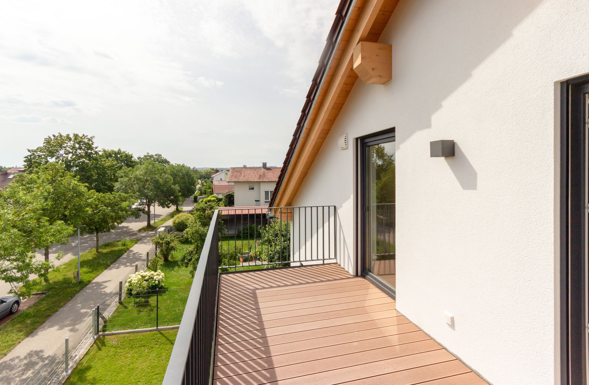 Ein Balkon mit Holzterrasse und einem weißen Gebäude im Hintergrund