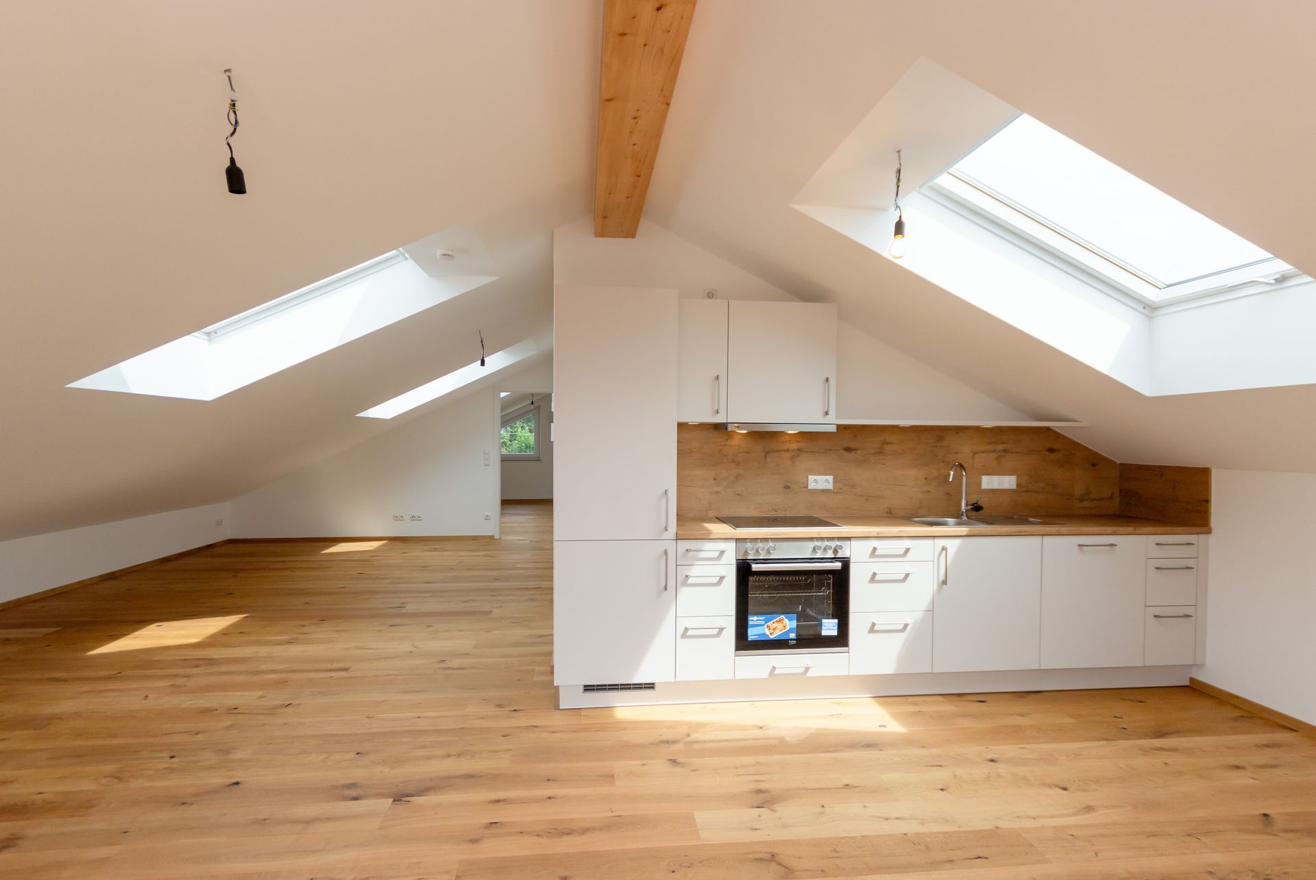 Eine Küche im Dachgeschoss mit Oberlicht und Holzböden.