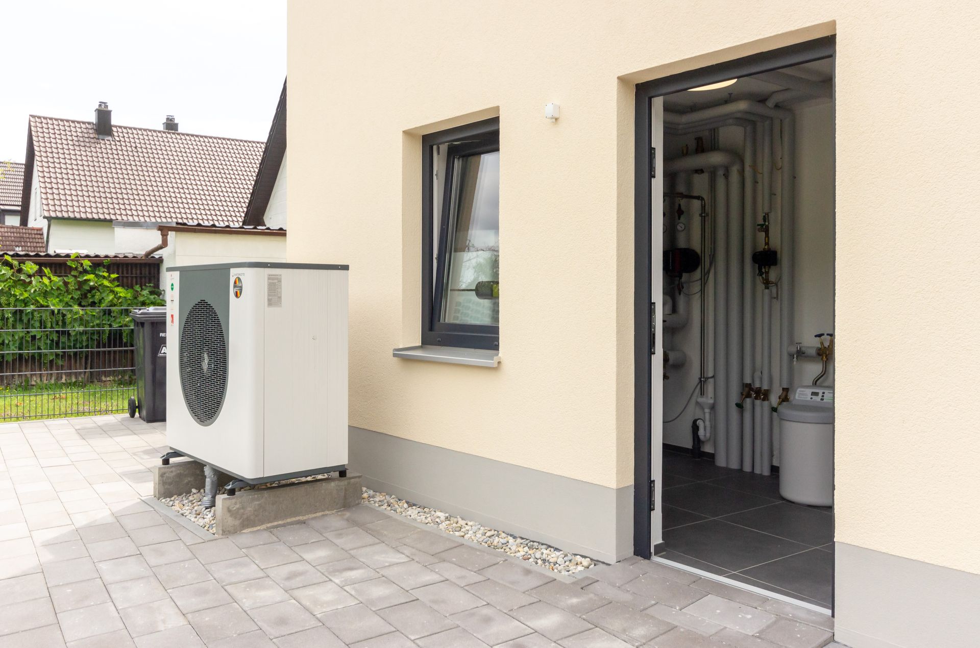 Eine weiße Klimaanlage steht an der Seite eines Gebäudes neben einem Fenster.