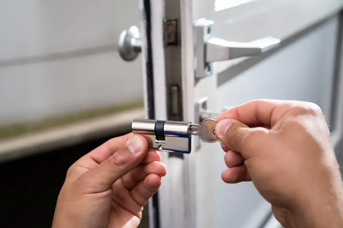Manos que sujetan un pestillo de metal plateado en una puerta o armario.