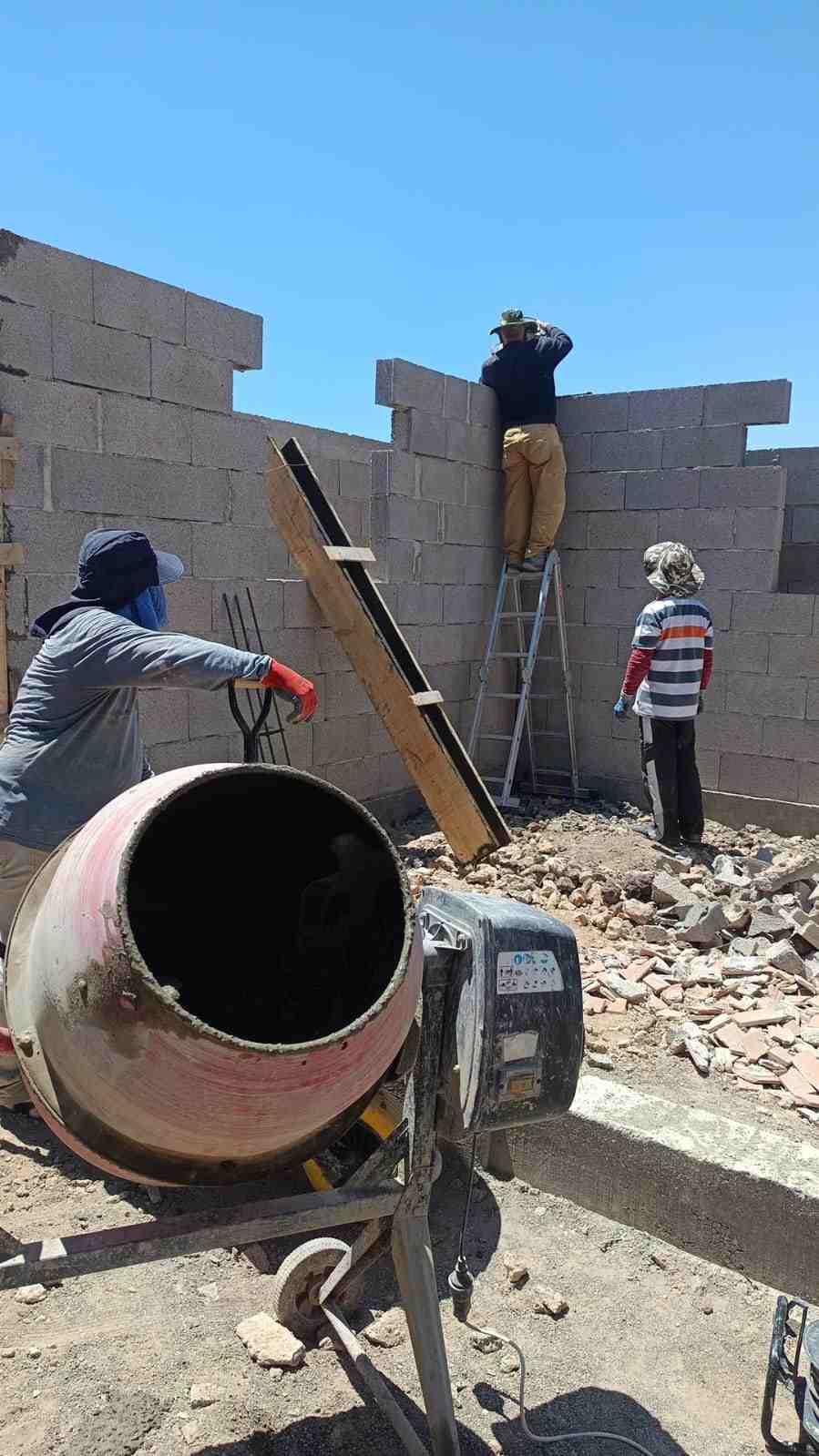 Obreros de la construcción en una obra de construcción de un muro de bloques de hormigón.
