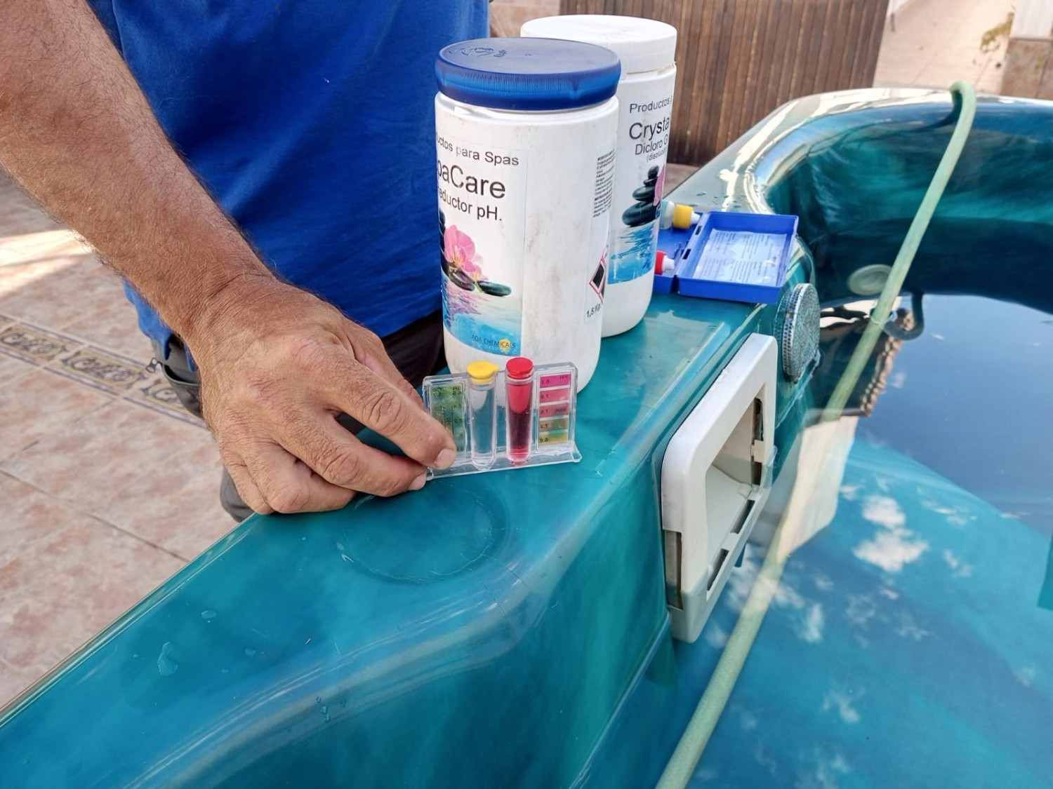 Una mano coloca pequeños frascos junto a botellas de medicamentos en el panel de control de un barco cerca del agua azul.