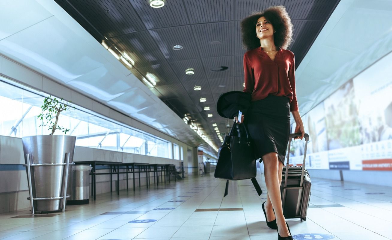 Una mujer camina por un aeropuerto con una maleta.