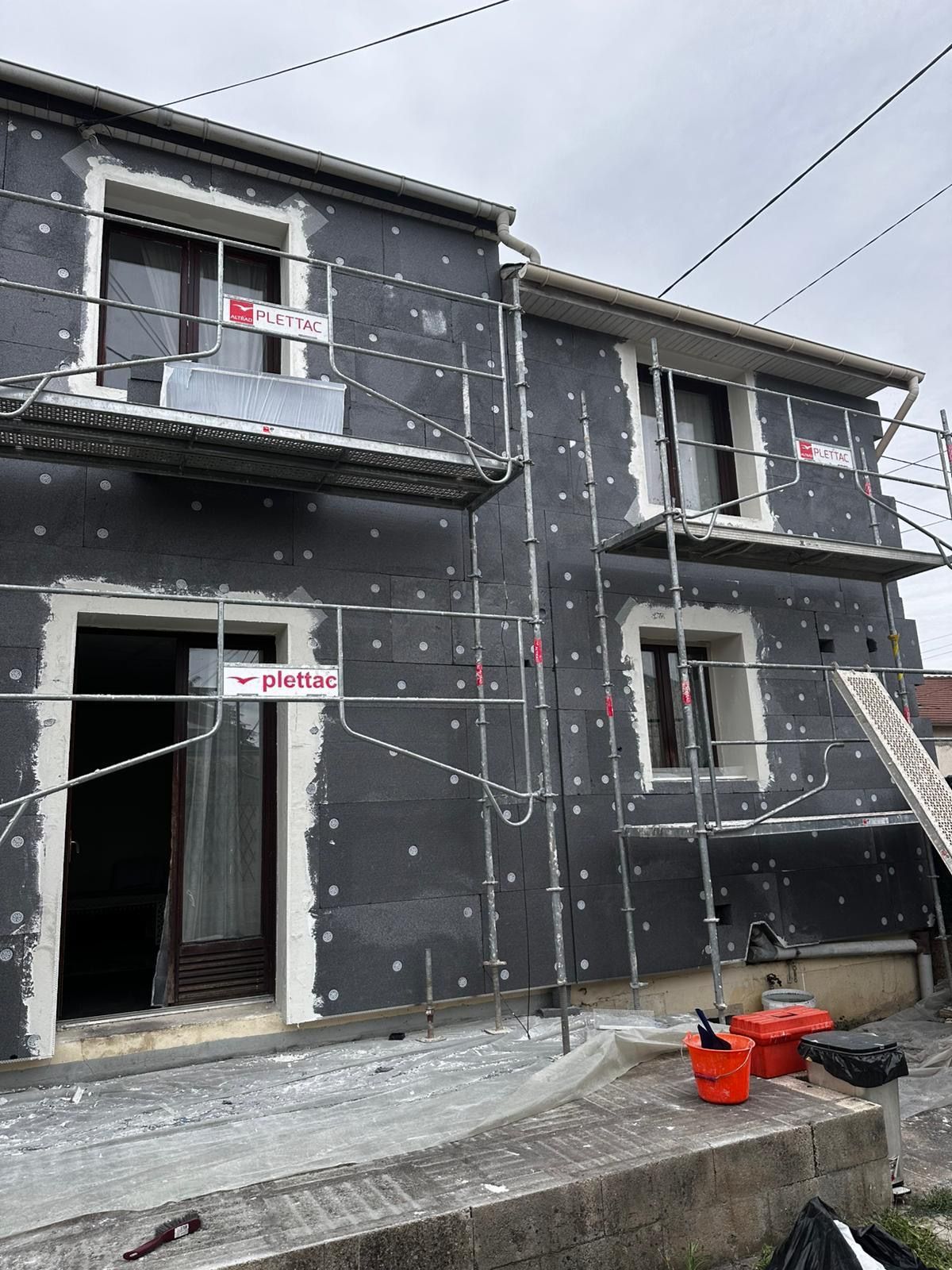 Maison extérieure en construction avec échafaudages et isolation.