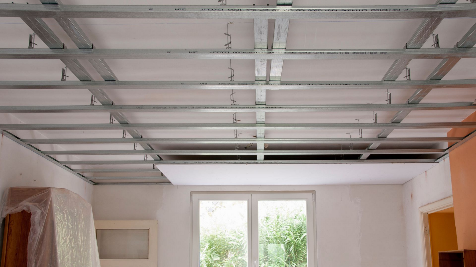 Ossature métallique pour un faux plafond dans une pièce avec fenêtre et porte.