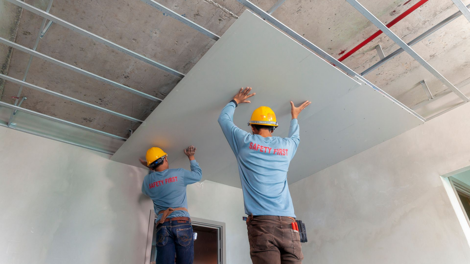 Deux ouvriers du bâtiment installent des plaques de plâtre.