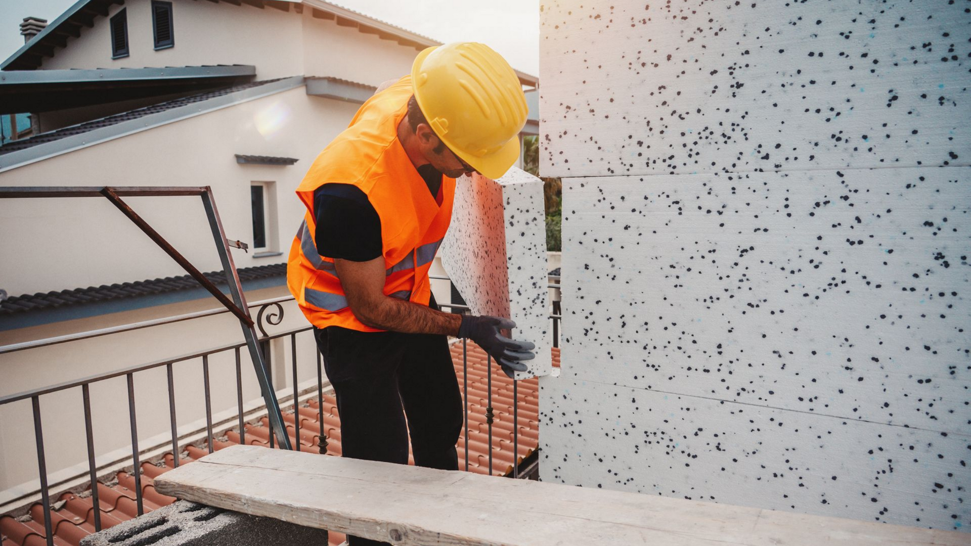 Ouvrier installant un isolant en mousse sur la façade d'un bâtiment.