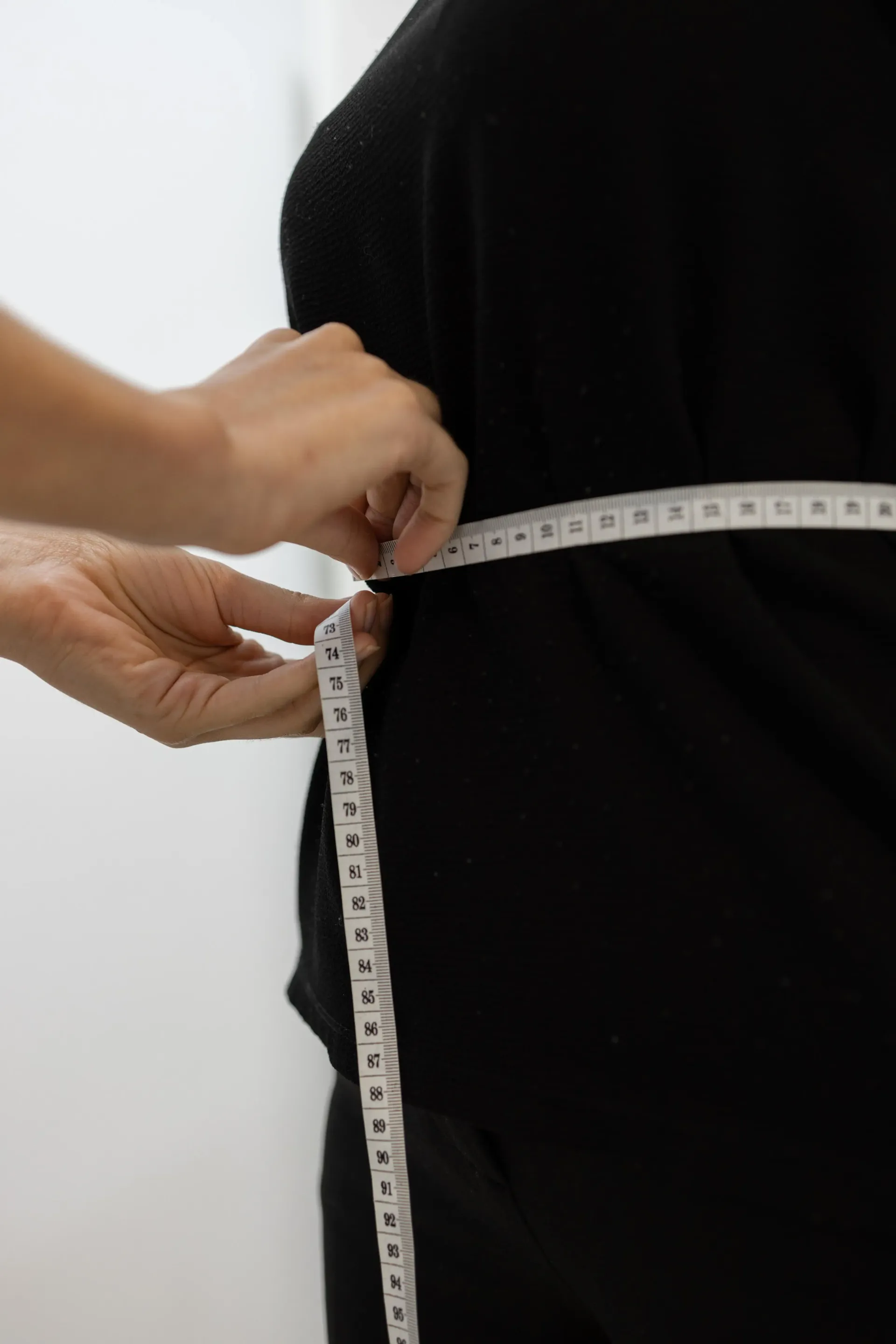 Cinta métrica alrededor de la cintura de una persona para medir la ropa.