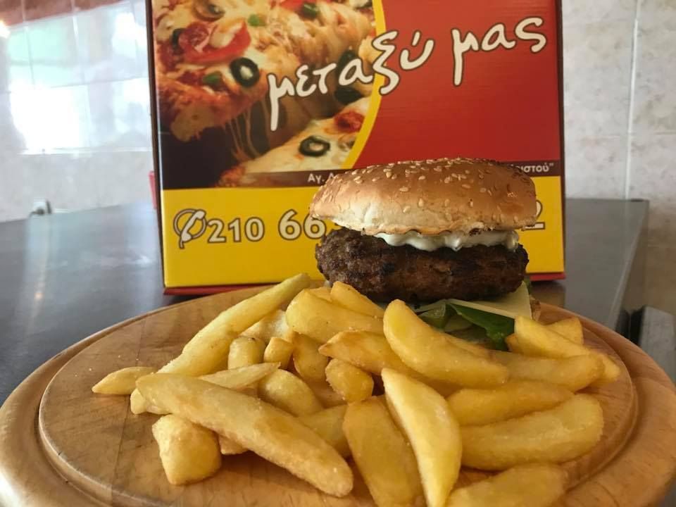 Μπιφτέκι και πατάτες σε ένα ξύλινο πιάτο μπροστά από μια κόκκινη και κίτρινη πινακίδα εστιατορίου.