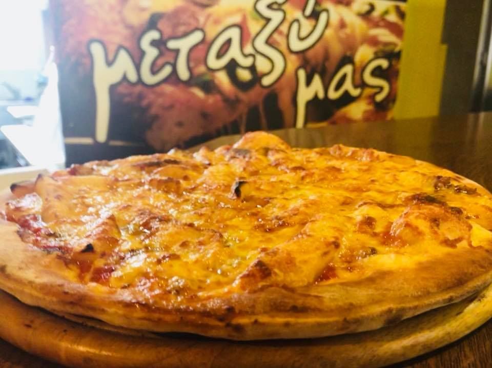 Φρέσκια τυρένια πίτσα σε ξύλινη σανίδα σε εστιατόριο