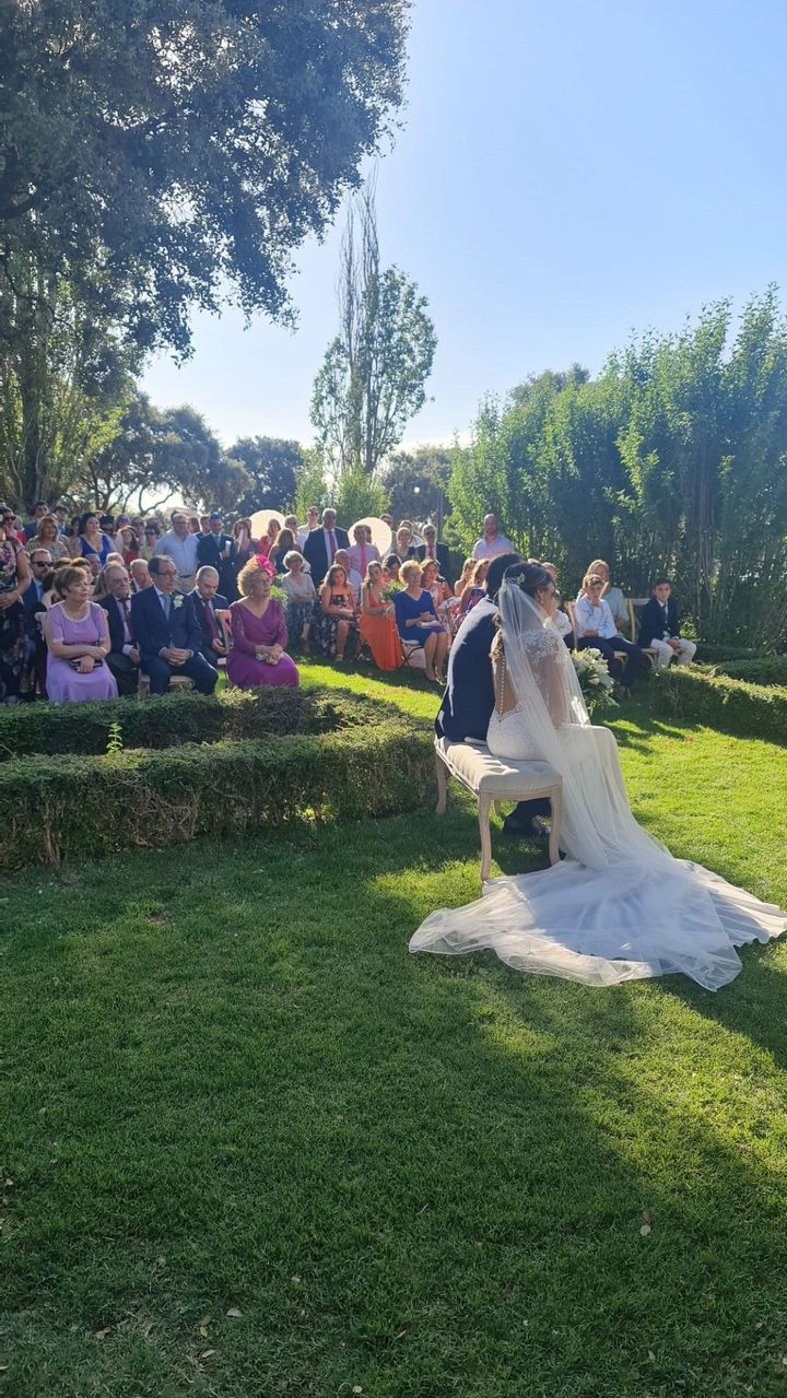 Una novia y un novio están sentados en un banco durante su ceremonia de boda.