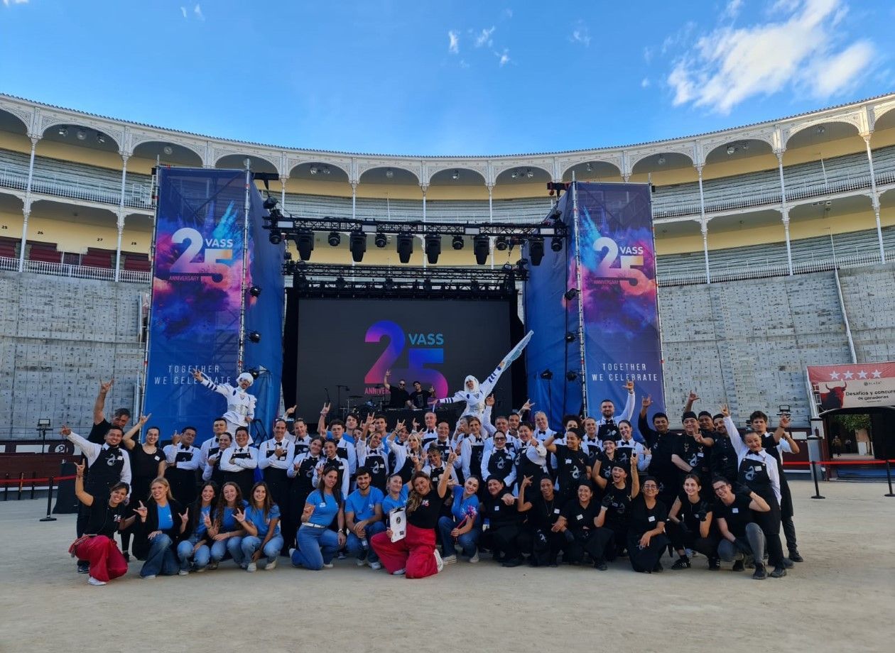 Un grupo de personas posa frente a un escenario con la leyenda 