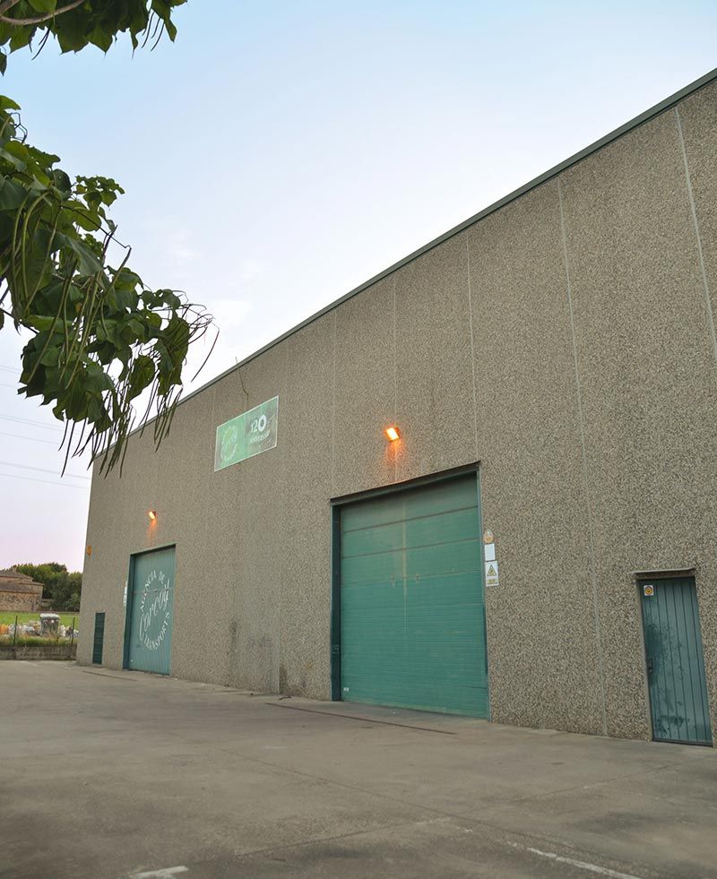 Un gran edificio blanco con techo verde está situado al lado de una carretera.