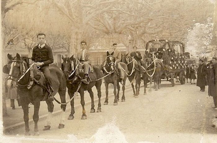 Un grupo de personas monta a caballo y tira de un carruaje por una calle.